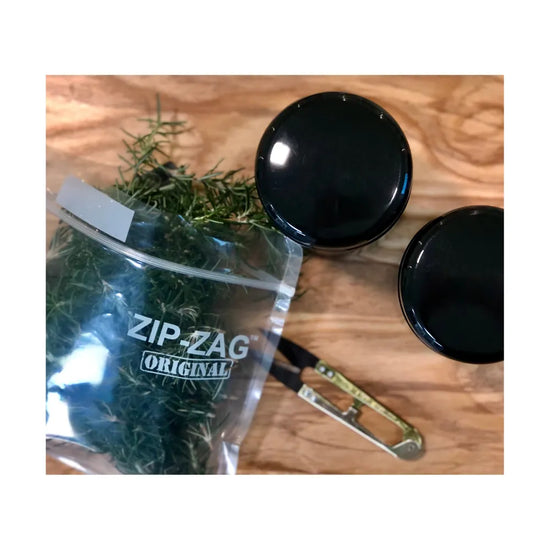 ZIP-ZAG resealable storage bag with fresh herbs on wooden surface, ideal for odour-resistant herb and accessory storage.