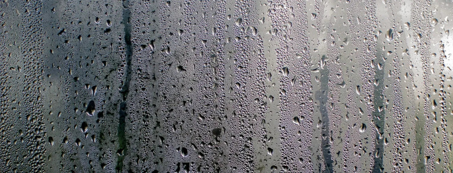 Heavy condensation and water droplets forming on a glass surface, illustrating high humidity and low VPD conditions in a grow room environment