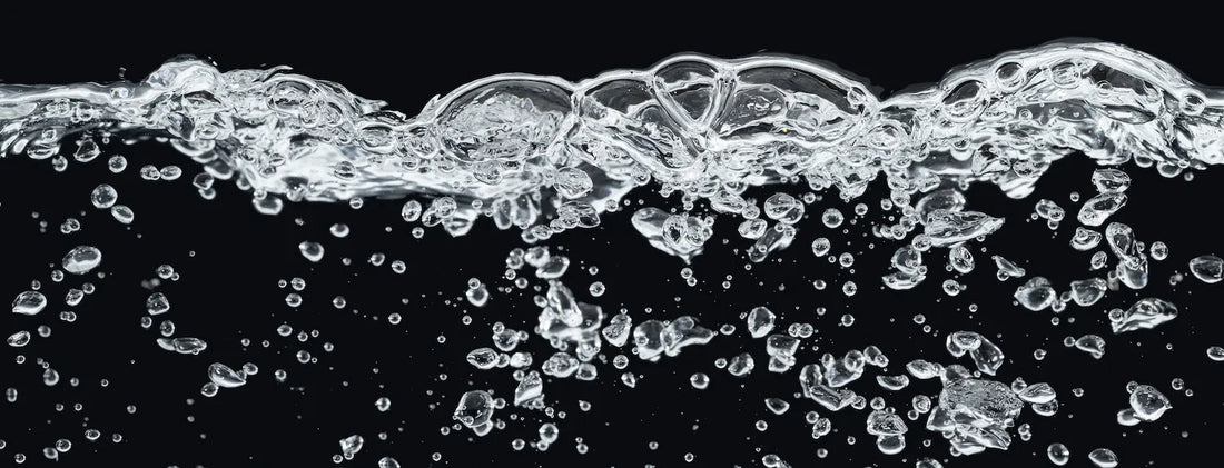 Aerated water with rising bubbles against a black background, representing dissolved oxygen levels in a DWC hydroponic reservoir