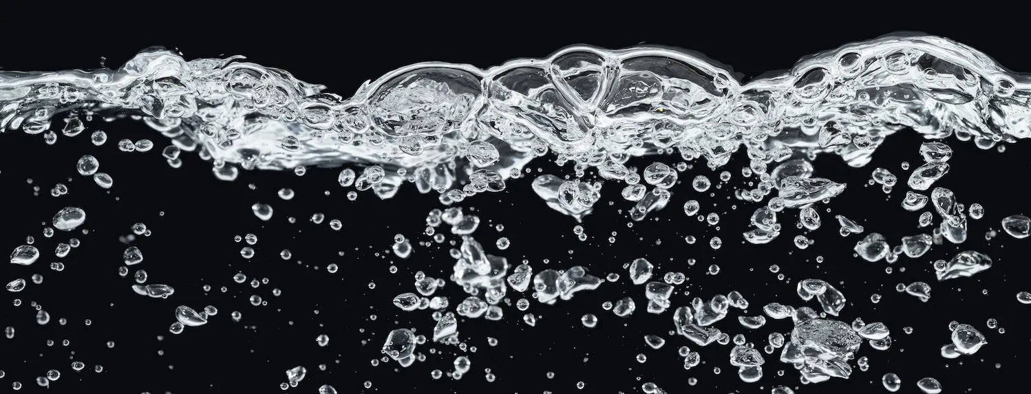 Aerated water with rising bubbles against a black background, representing dissolved oxygen levels in a DWC hydroponic reservoir