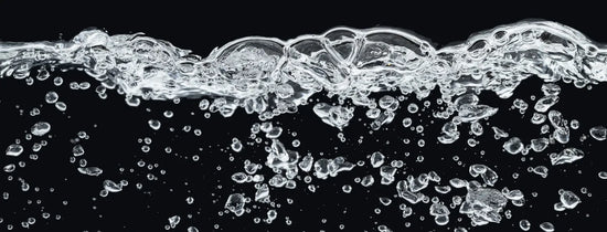 Aerated water with rising bubbles against a black background, representing dissolved oxygen levels in a DWC hydroponic reservoir